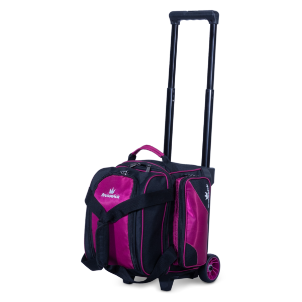 A single ball roller bag in raspberry and black upright three quarter view facing left with handle extended.