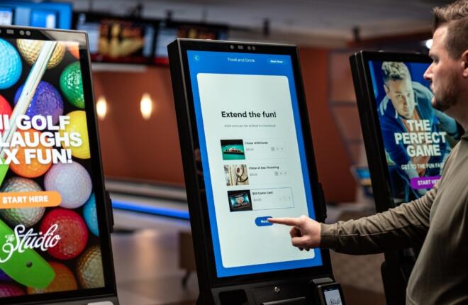 Three kiosks with ads and food menu, person points at middle screen.