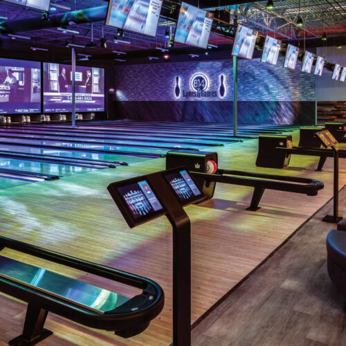 colorful bowling lanes with tvs and projector screens at end of lanes