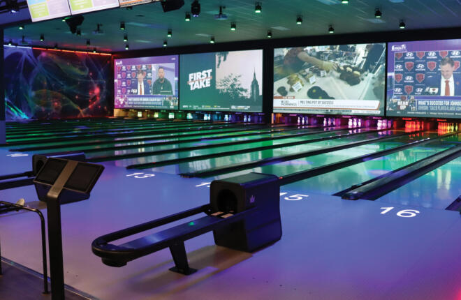 Bowling lanes with TV screens and colorful lighting.