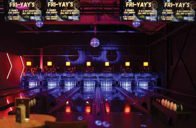 Front view of multiple bowling lanes with digital scoring screens, vibrant lighting, and a high-energy nightlife atmosphere.