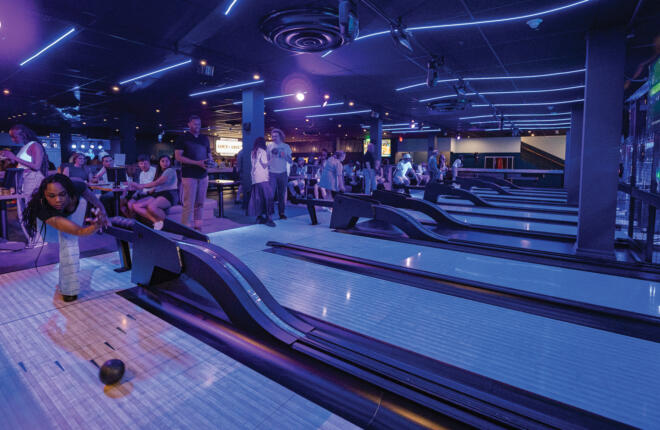 Bowlers enjoying games at Broughton Street Bowl Savannah Georgia with purple LED ceiling lights and modern decor