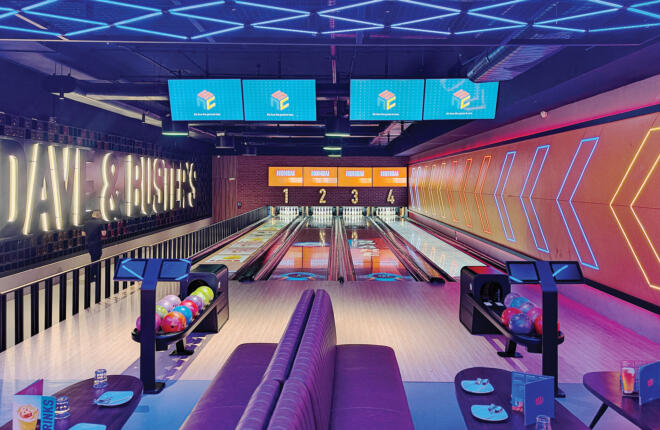 Bowling alley with digital screens, colorful balls, and neon lighting.