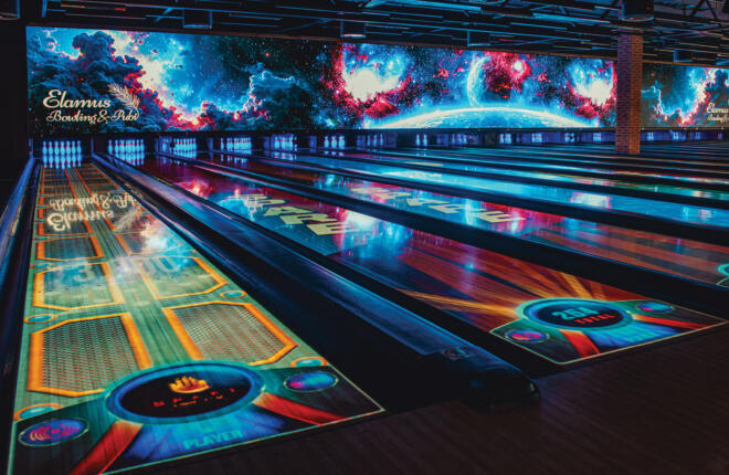 Spark immersive bowling lanes with animated lane projections and a large LED video wall in a high-energy bowling venue.
