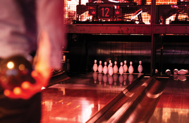 Bowling alley lane with pins set up, illuminated by red lighting, lane 12