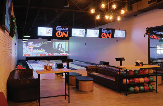 view from the bowlers area of bowling lanes with ball rack and seating