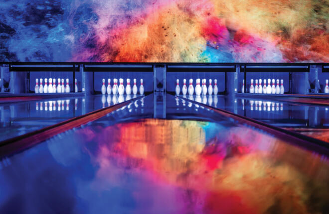 Bowling lanes, colorful cosmic-themed light display reflecting polished floors