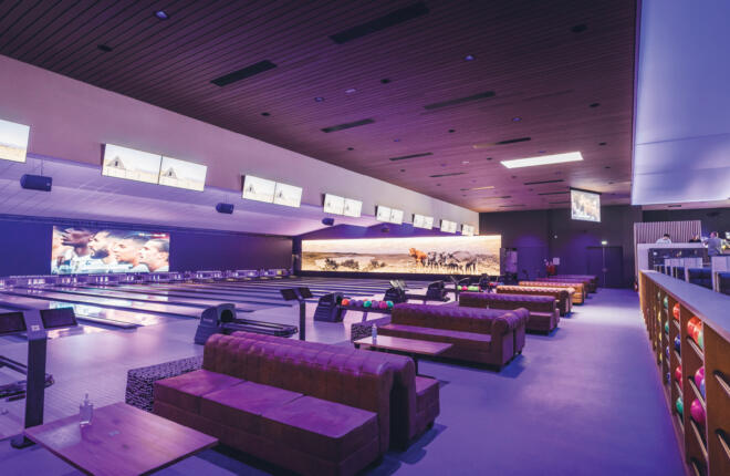 Lanes under black light, seating, ball returns, Sync tablets & cattle mural.