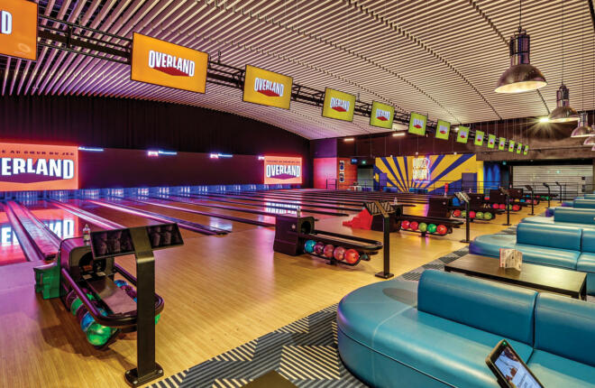 Modern bowling alley interior with colorful LED lighting, blue seating areas, and Overland branded lanes in Pontault-Combault, France