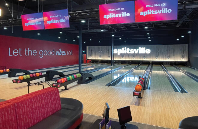 Wide view of Splitsville bowling lanes with branded wall graphics and ball returns.
