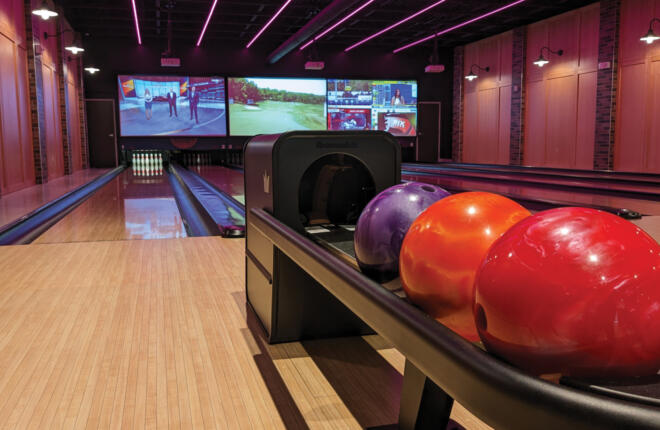 close up of a ball return with 3 bowling balls on it