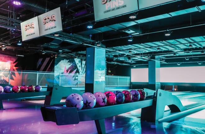 Colorful bowling alley with neon lights and bowling balls on racks.