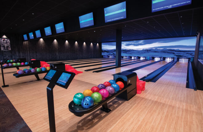 Bowling alley with colorful balls and lit scoreboards