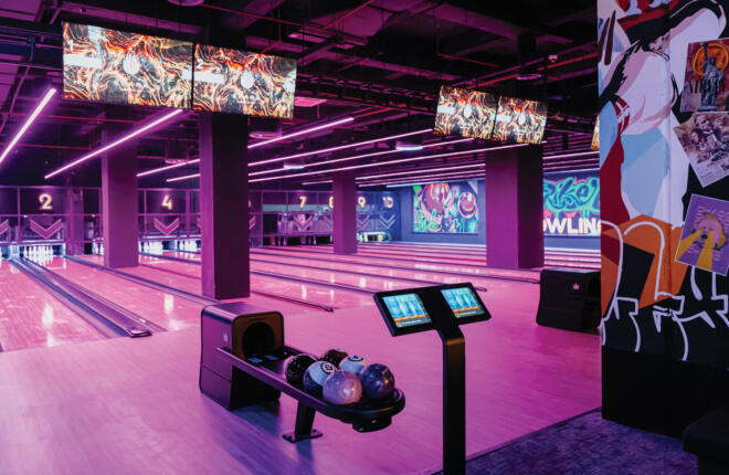Multiple bowling lanes with digital displays and illuminated pins.