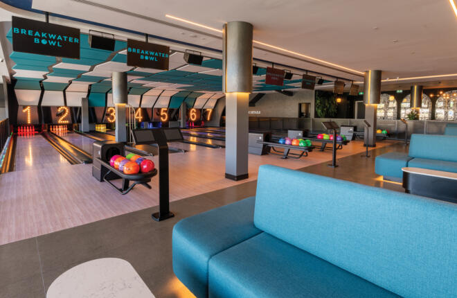 Upscale bowling venue with bright turquoise ceiling panels and lounge area.