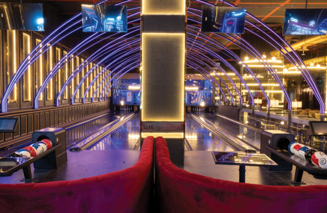 view from behind brunswick bowling lanes with red soft seating and ball returns