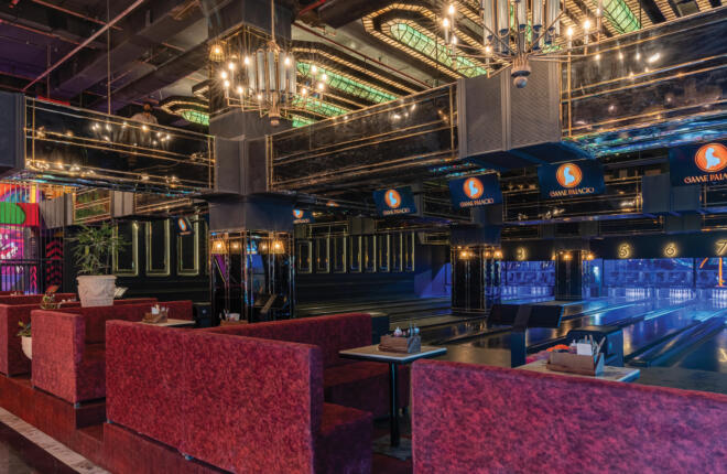 Upscale bowling alley with plush red booths, chandeliers, reflective surfaces.