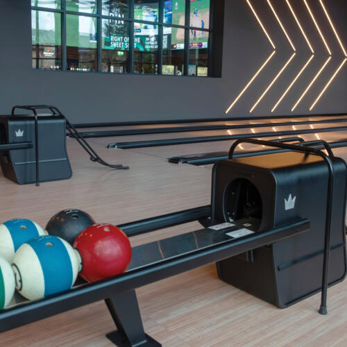Modern bowling ball returns and lanes with sleek design, integrated lighting, and a contemporary entertainment atmosphere.
