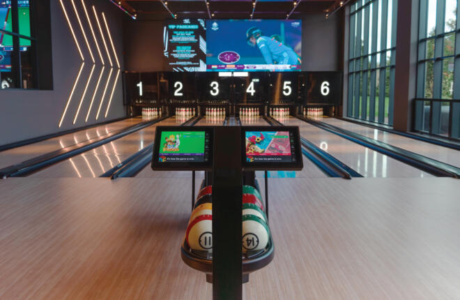 High-end bowling lanes with digital scoring screens, ambient wall lighting, and immersive video displays.