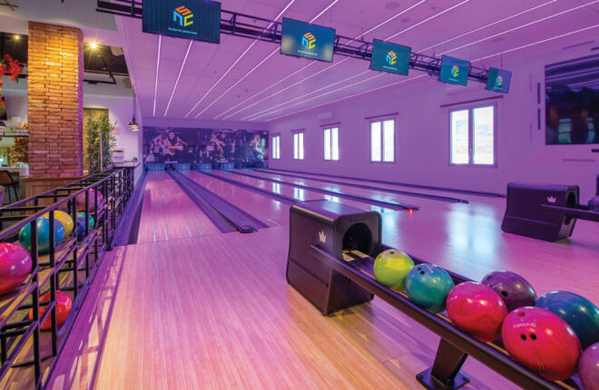 Bowling lanes with pink lighting and ball returns