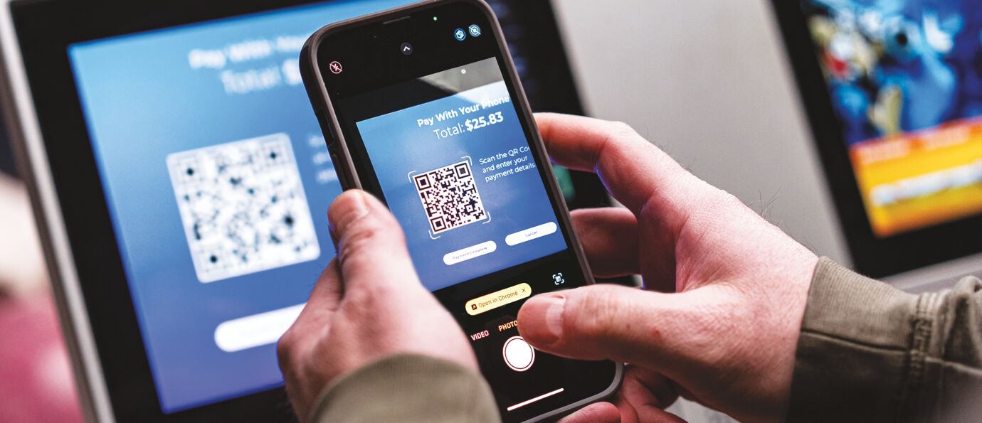 Customer scans a QR code on the Sync scoring tablet screen with their phone to complete a payment.