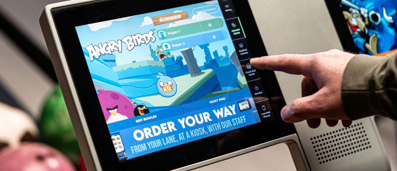 Guest interacts with a Sync scoring screen showing Angry Birds bowling game and order options.