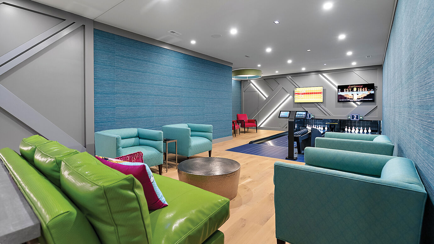 A stylish home entertainment space featuring two private bowling lanes with Sync Scoring by Brunswick Bowling, surrounded by teal and lime-green modern seating under recessed lighting.