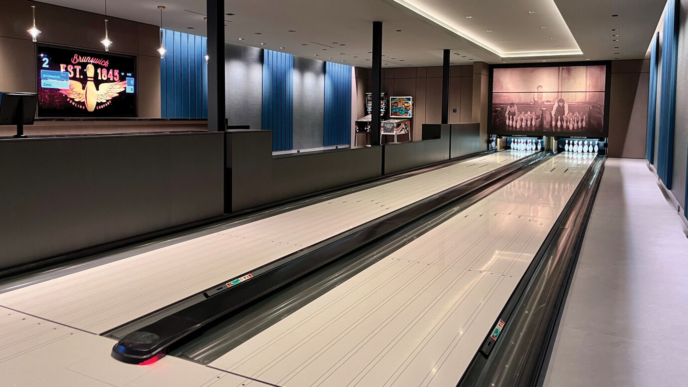 Modern bowling alley with two lanes, vintage mural masking units, digital scoreboard, and blue wall panels.