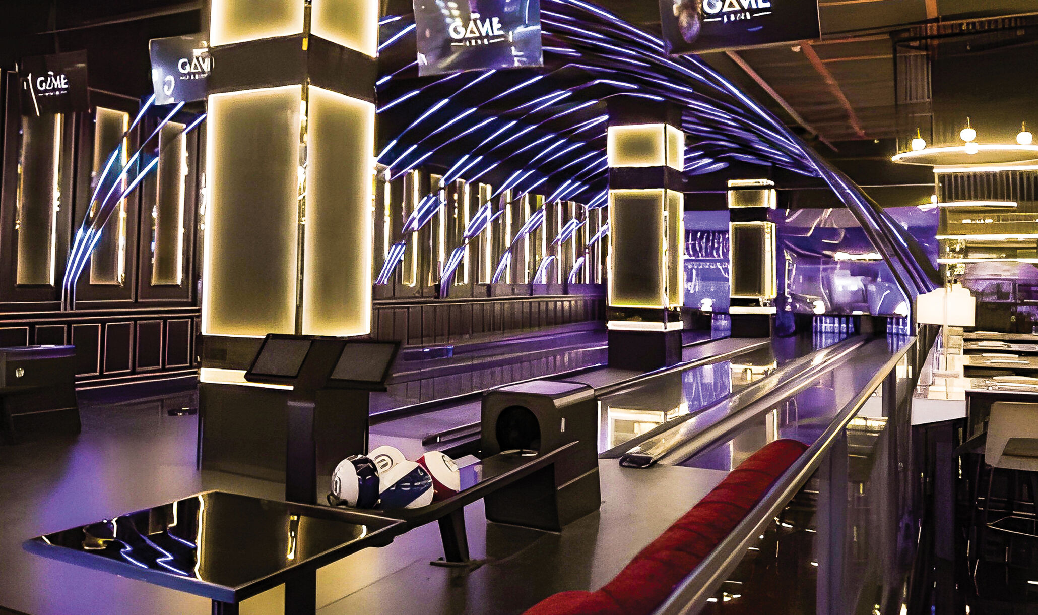 four brunswick bowling lanes with lighting columns in between lanes, neon lights