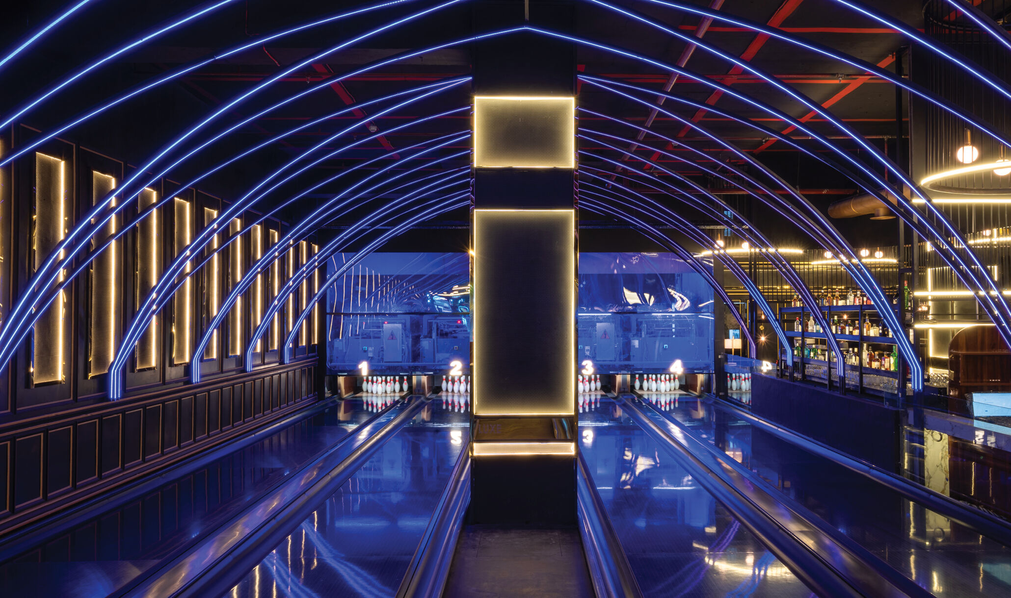 Overhead view of four bowling lanes with blue and white strip lighting