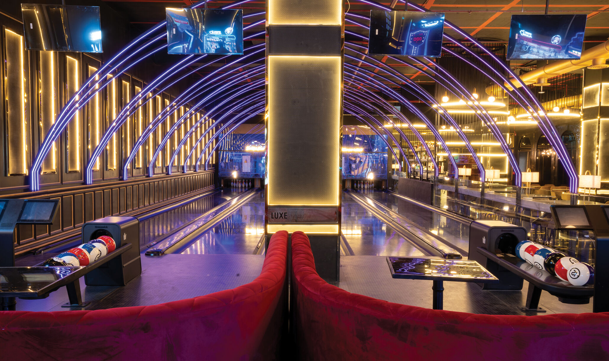 view from behind brunswick bowling lanes with red soft seating and ball returns